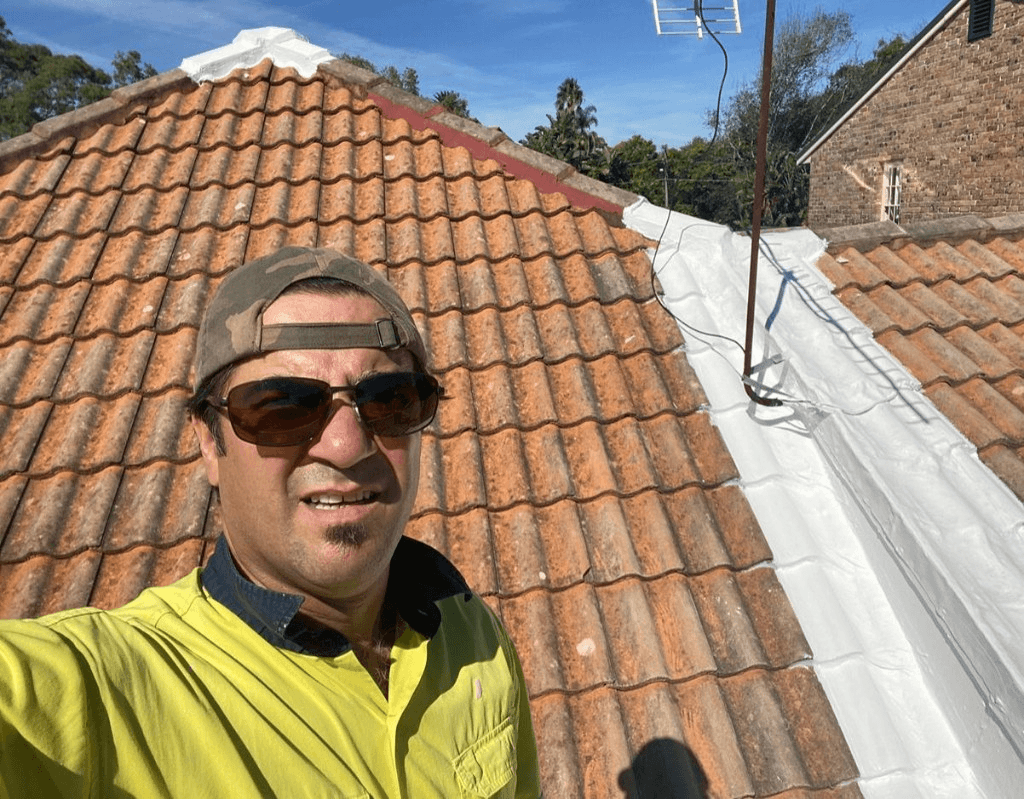 Issac Zorzano applying roof waterproofing on a tiled roof