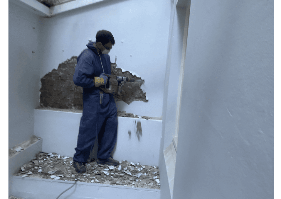 Preparing basement brick wall by removing plaster before negative pressure membrane application