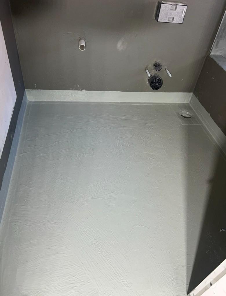 Bathroom floor coated with waterproofing membrane and coved edges up the walls