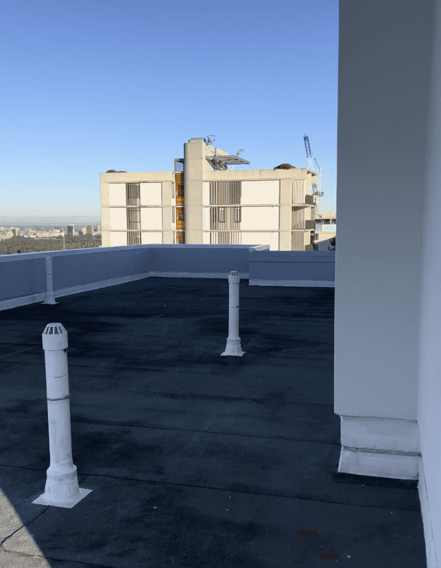 Completed flat roof with waterproofed parapets and sealed vents at Bondi Junction